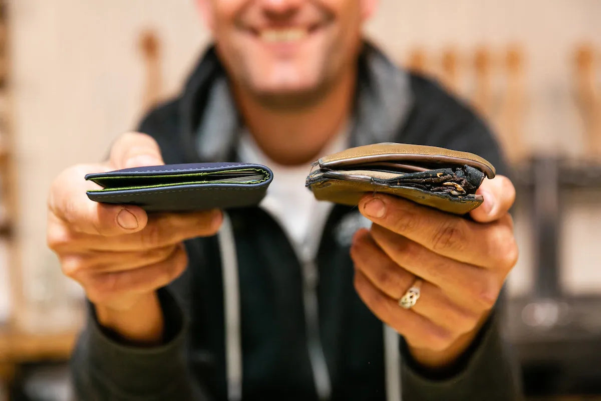 Man holding two wallets side by side. On the left is a thin wallet filled with cards. On the right is a much thicker wallet that is in disrepair.
