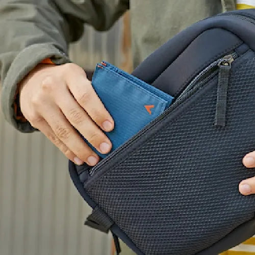 Man is slipping a slim light blue wallet from Allett into their rounded rectangular bag.