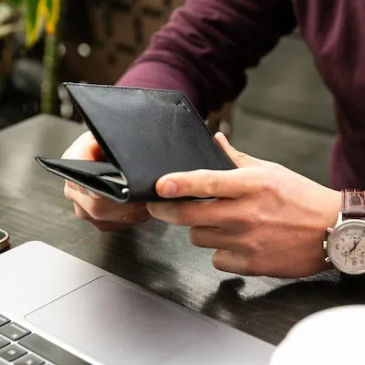 Hands holding a larger wallet that still has a slim profile and holds over a dozen cards and cash.