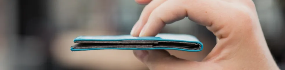 Hand holding an incredibly thin light blue wallet from Allett.