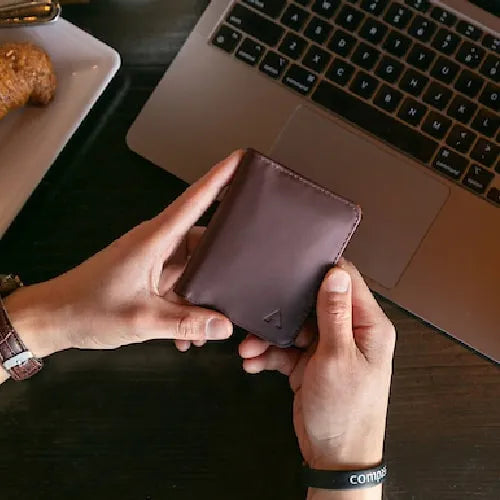 Hands holding one of Allett's designer leather wallets. Wallet brown and made with Nappa Leather.
