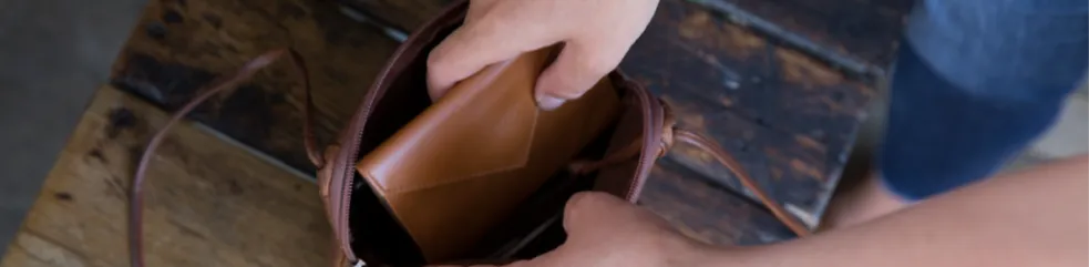 Woman takes a slim leather wallet from Allett Wallets out of her purse.