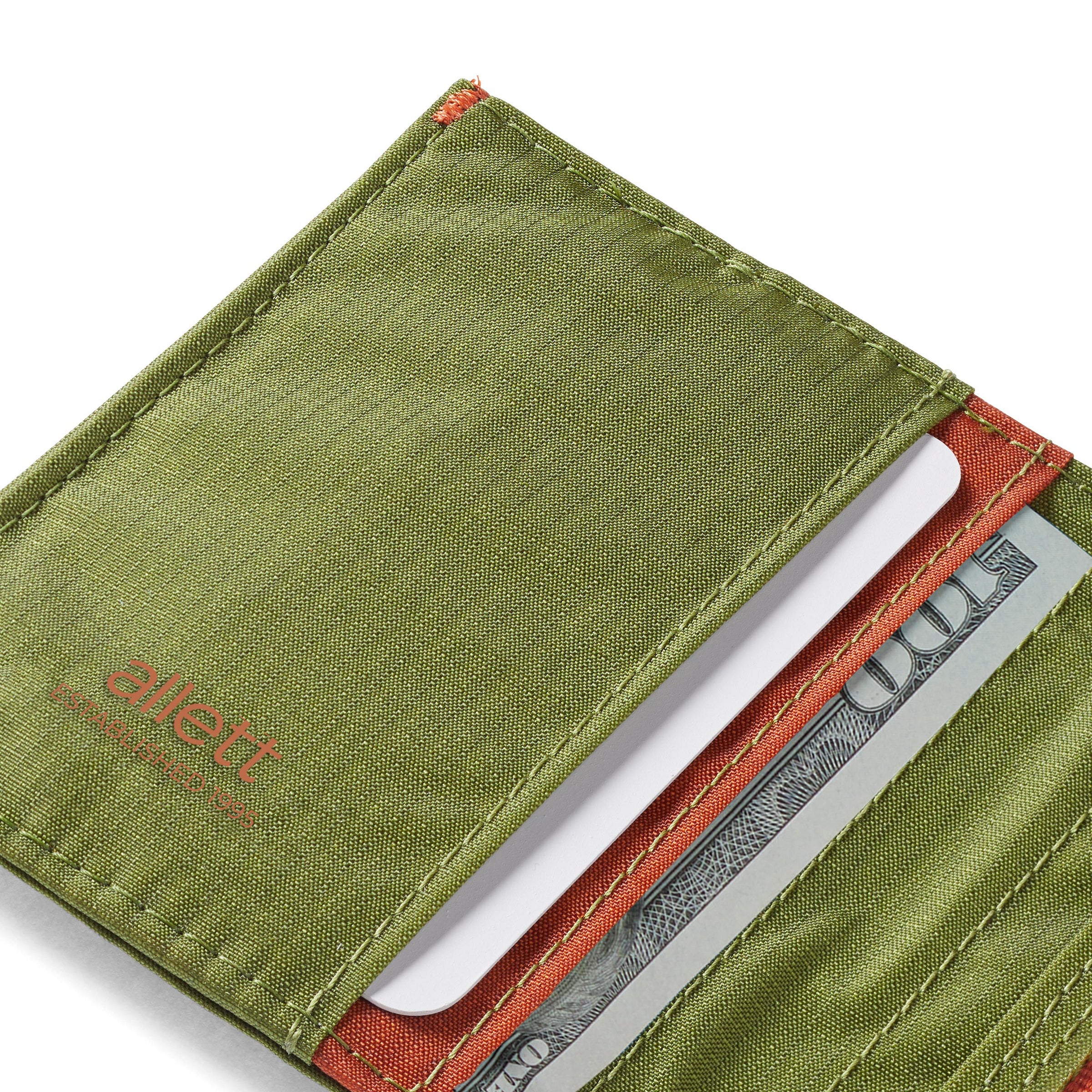 Green Allett wallet with money and card inside on a white background