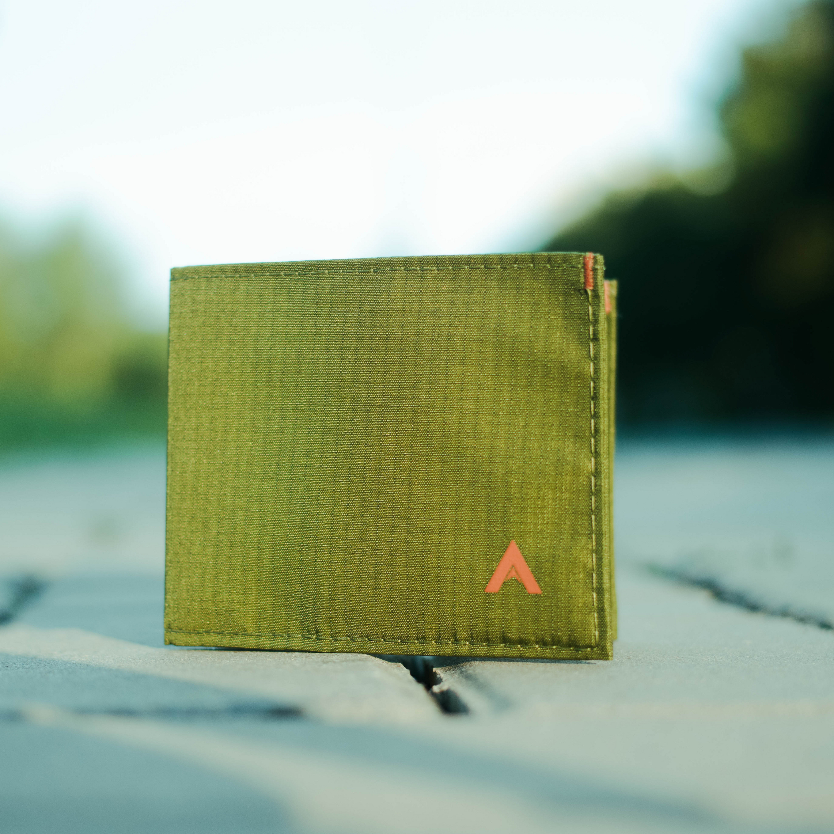 Allett RFID Blocking Green nylon wallet with a logo on a blurred natural background