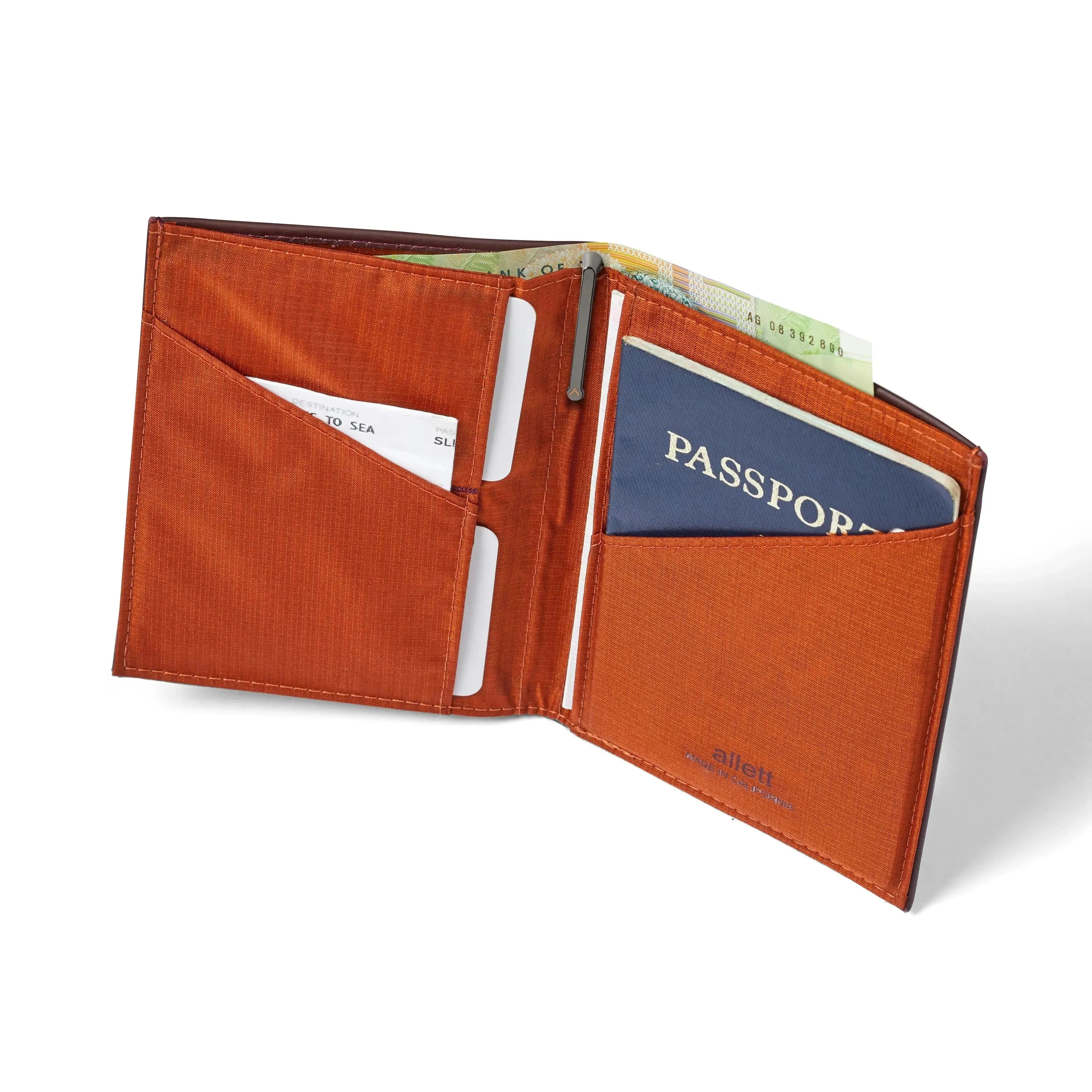 Open merlot Nappa leather travel wallet by Allett, holding a passport on the right, cards and an airplane ticket on the left, and currency sticking out from the top nylon-lined cash pocket. Leather Travel Wallet for passport rfid security - merlot