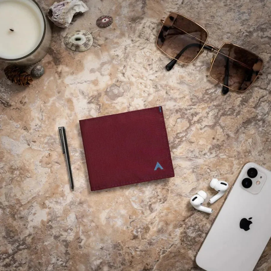 Photo shows a wallet next to a small micro pen on a table with other accessories - ID wallet made in mulberry color vegan nylon -Allett ID Wallet Nylon RFID mulberry