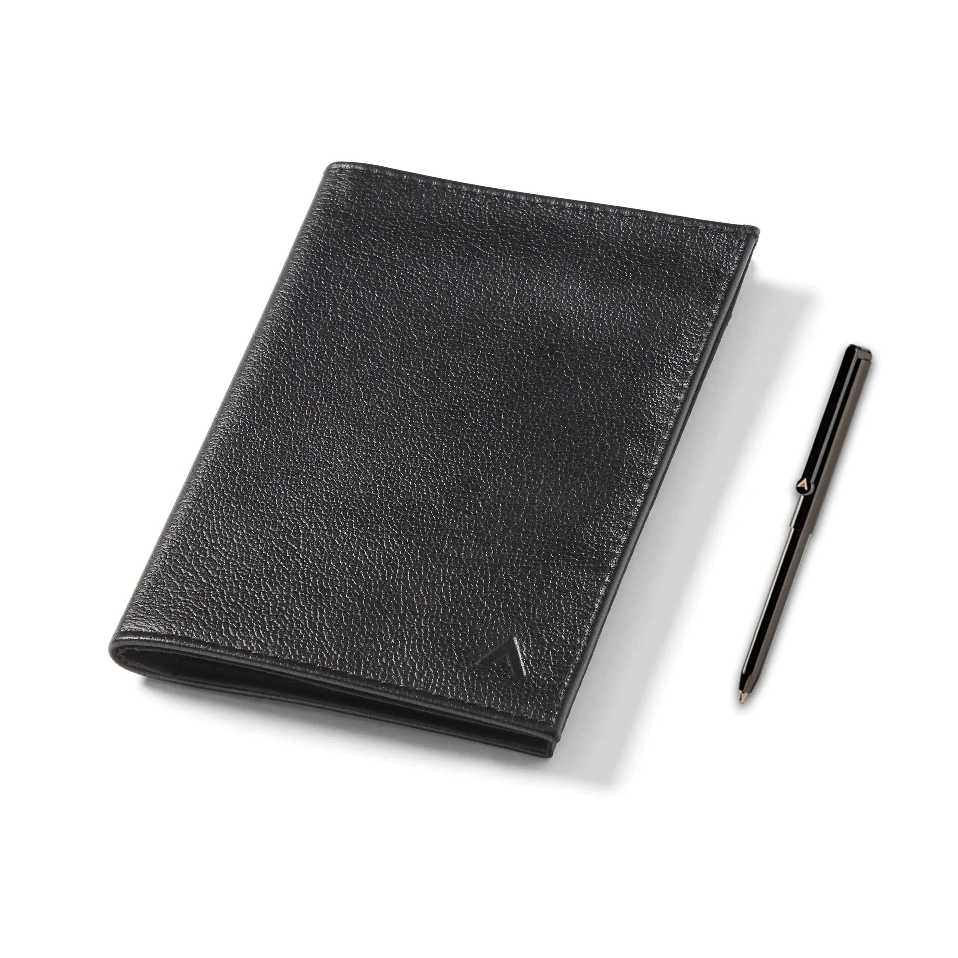 Closed leather Allett black Nappa leather passport wallet next to a small micro pen that can be purchased with the wallet. - black pen