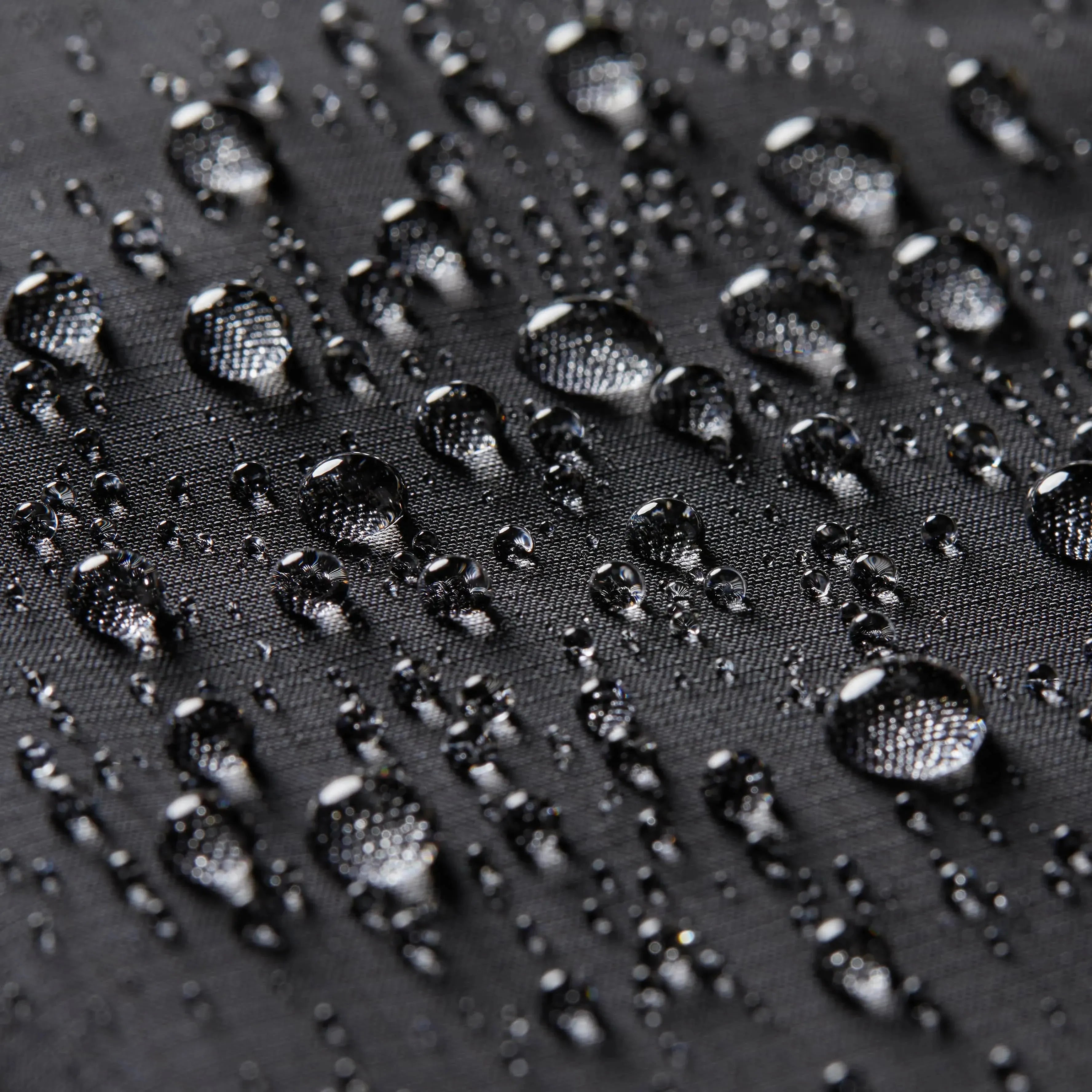 Close up of the Allett logo against the nylon interior of the black passport wallet, with some droplets to showcase the wallet's waterproofing - black