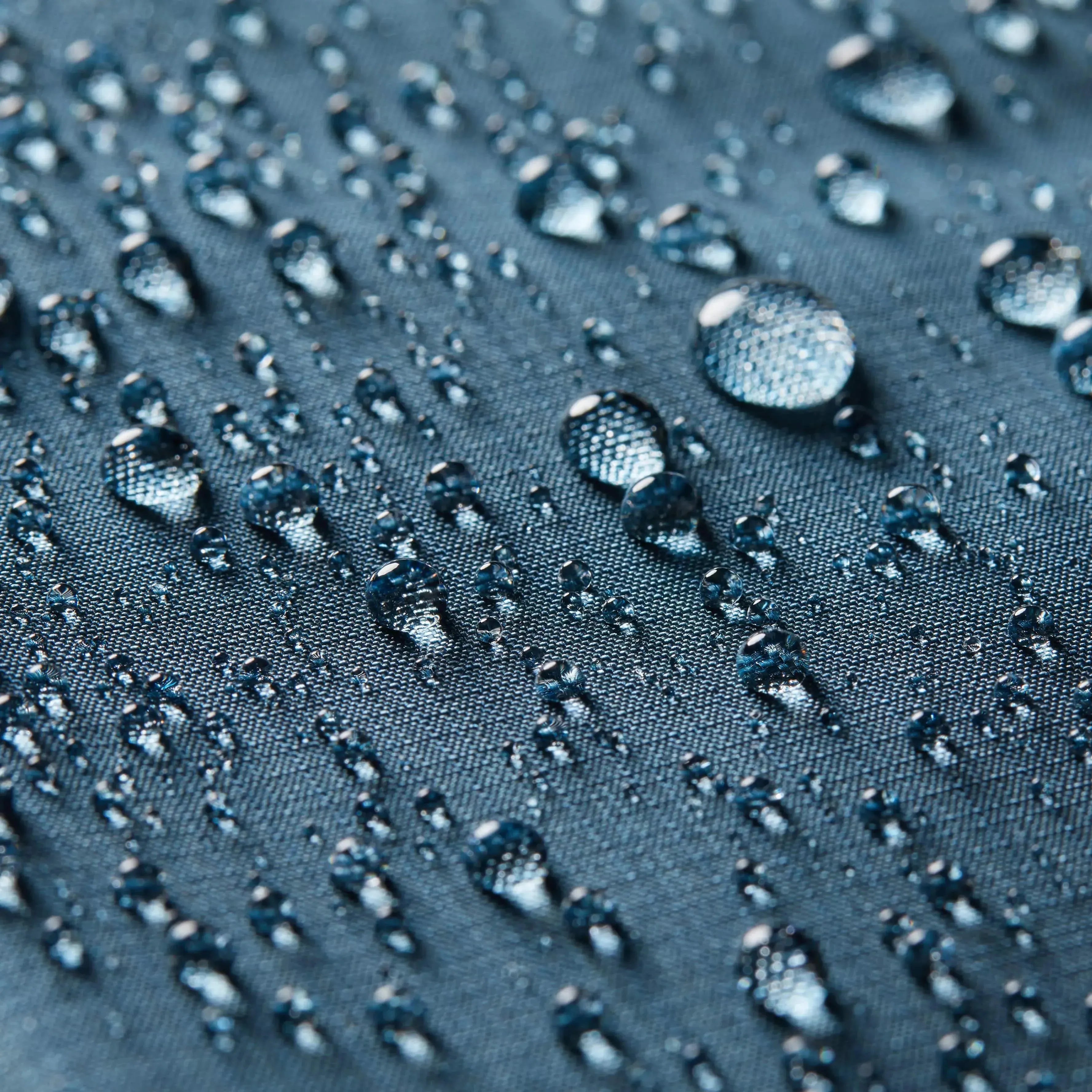 Conceptual picture highlighting water beads on the nylon surface of an indigo blue coin wallet, with the Allett logo faintly visible in orange. allett coin wallet 2.0 indigo-blue