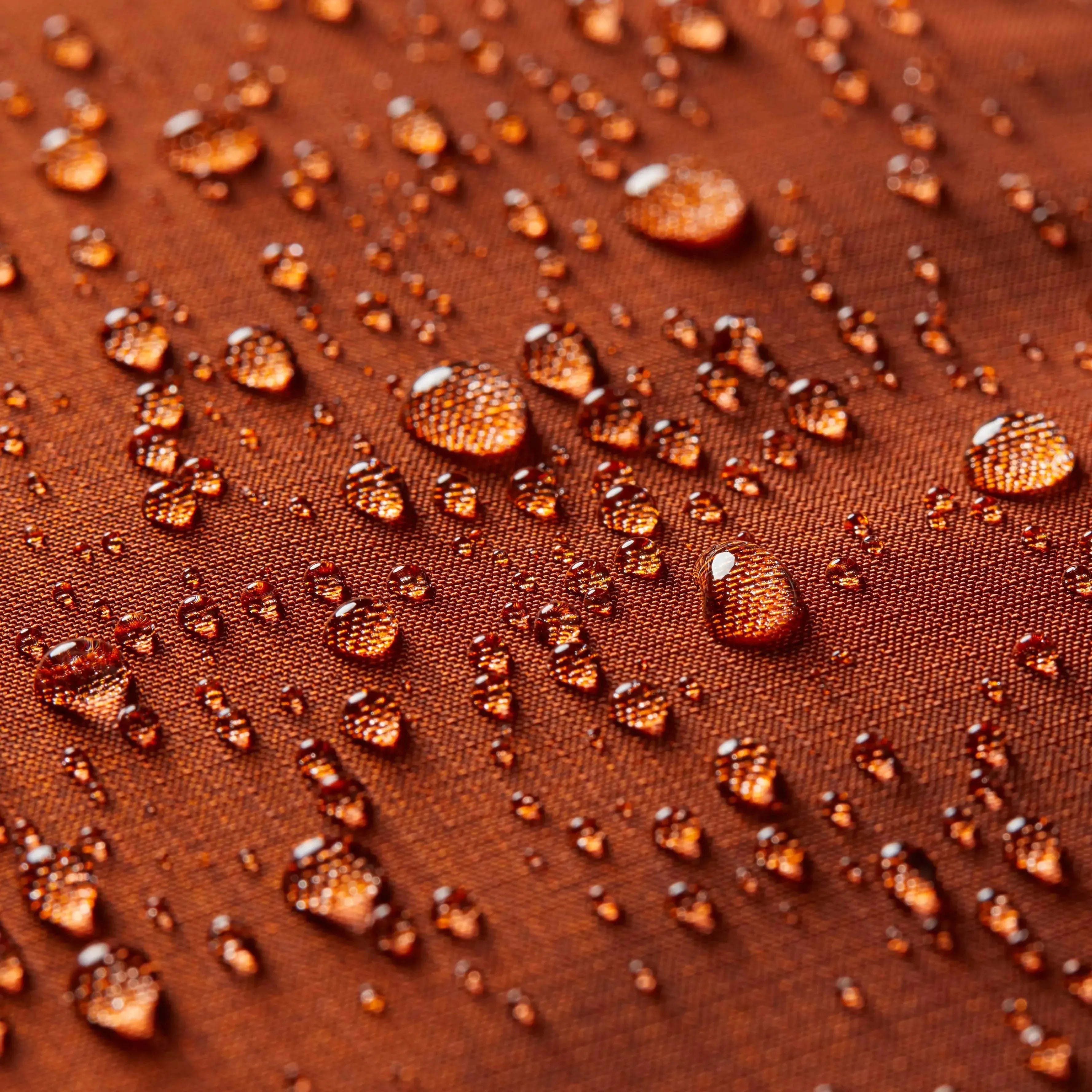 Ultra close up of the Allett wallet logo in the merlot leather wallet, with orange nylon surrounded by small water droplets to act as a concept to show waterproofing. Allett leather original wallet merlot