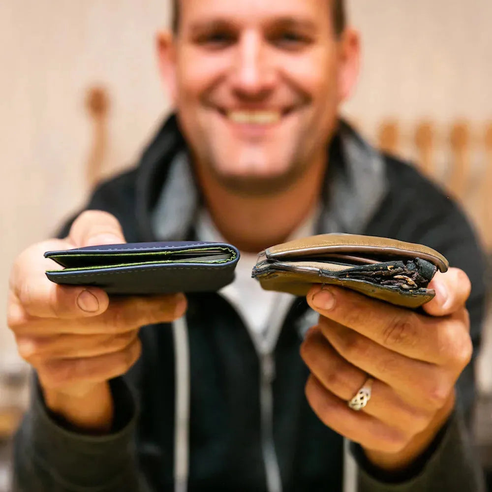One person holding up two different wallets to show the size and slimness differences between wallets, with the left side slimmer. Allett Leather Original Wallet- onyx-black merlot midnight-blue