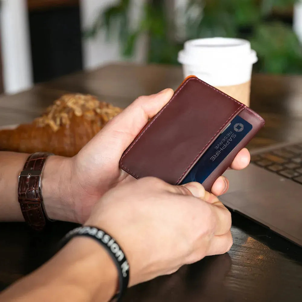 Two hands taking a Chase credit card out of the exterior pocket of the hybrid leather card wallet by Allett. Allett hybrid card wallet leather- merlot