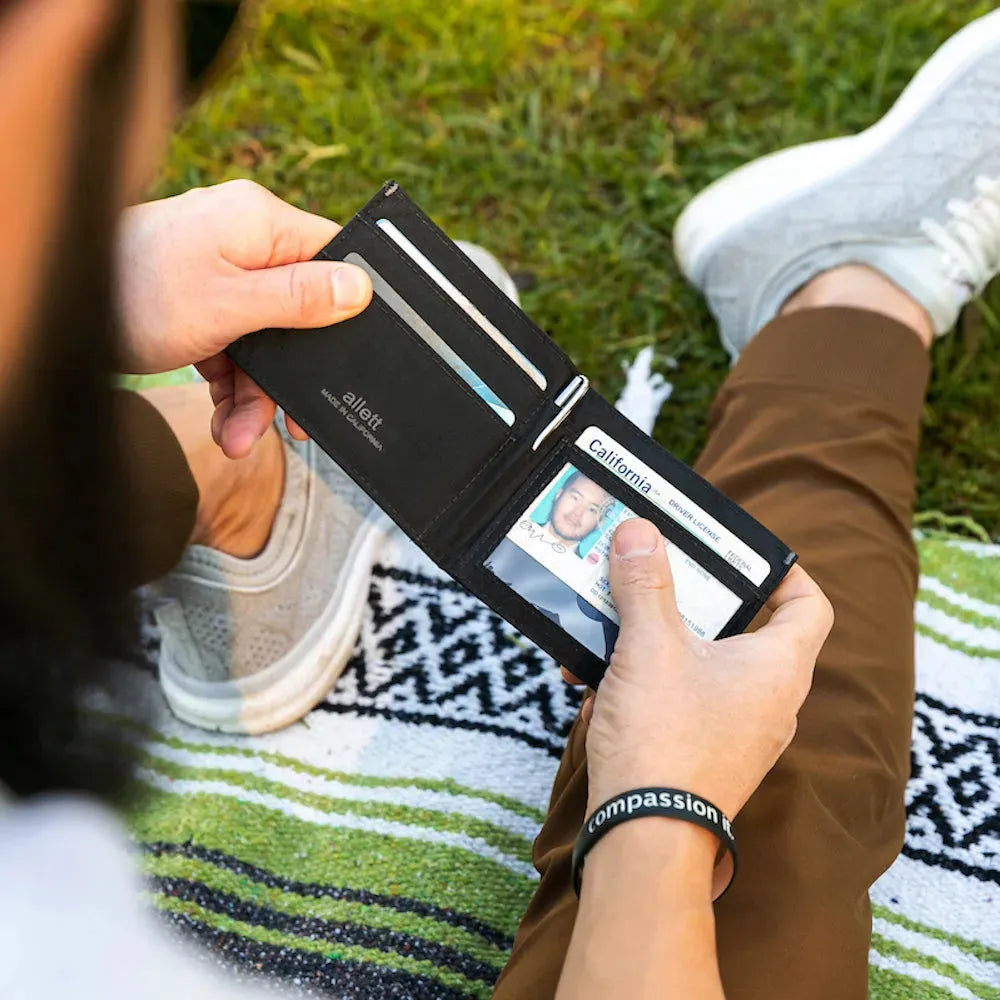 Person holding a jet black nylon ID wallet and looking at their California state ID through the clear ID cover - Allett ID Wallet Nylon RFID jet-black