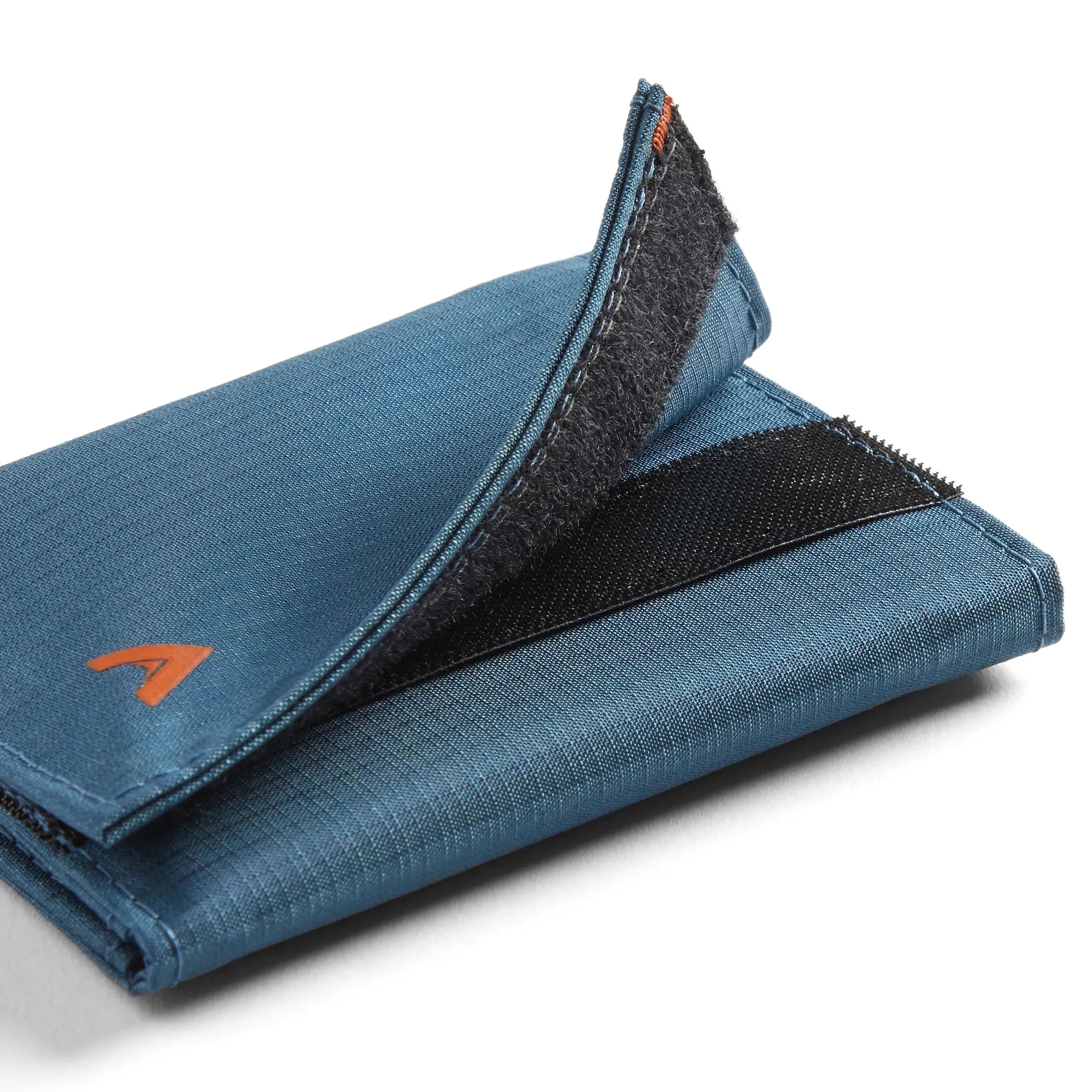 Nylon trifold wallet in indigo blue with the velcro flap partially ajar, captured in a semi-close-up against a white surface. Allett Trifold Wallet nylon edition - indigo-blue