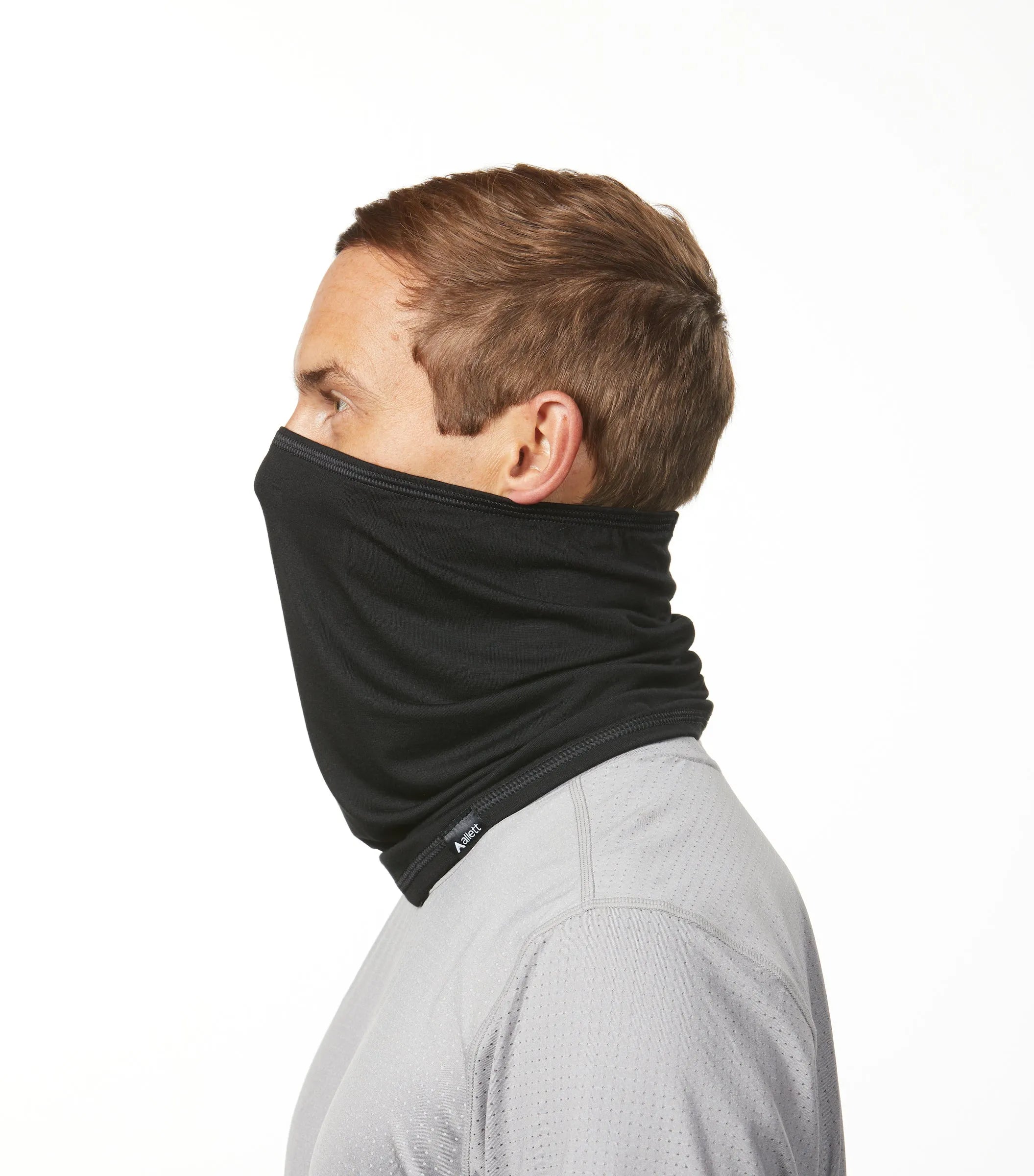 Profile view of a man wearing a black neck gaiter from Allett. black