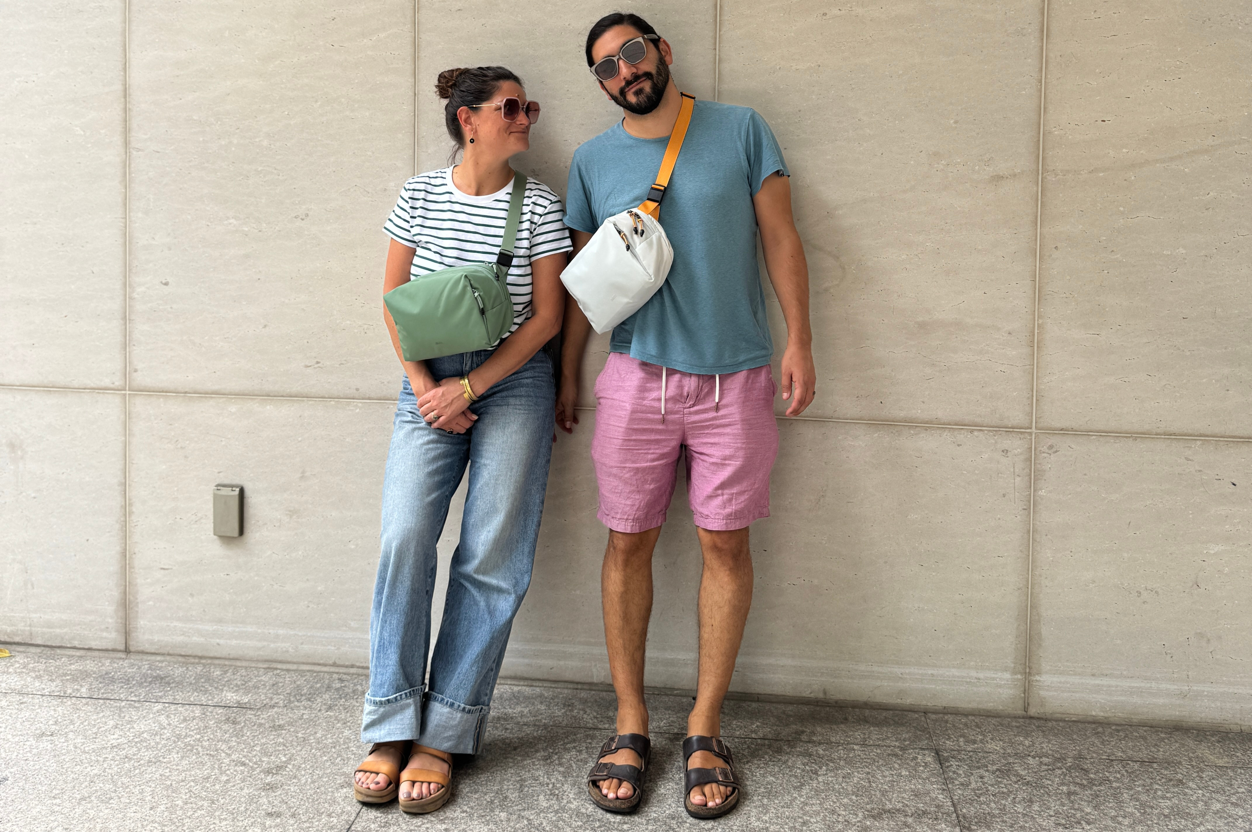 Man and woman wearing Allett sling bags leaning on a wallet, Top 10 best holiday gifts on a budget