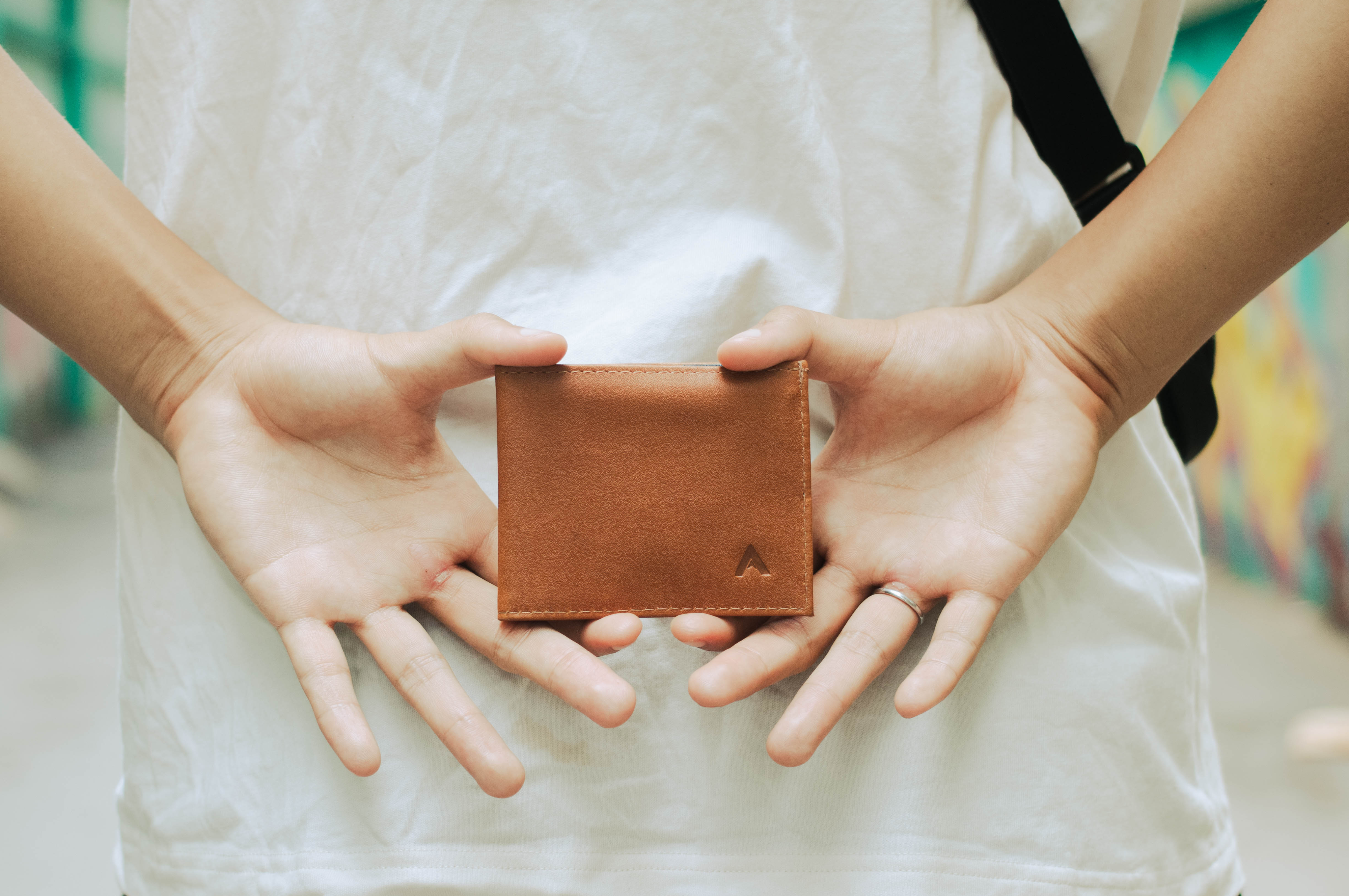 Hands holding a leather slim Allett wallet behind the back, Best Gifts for minimalists 