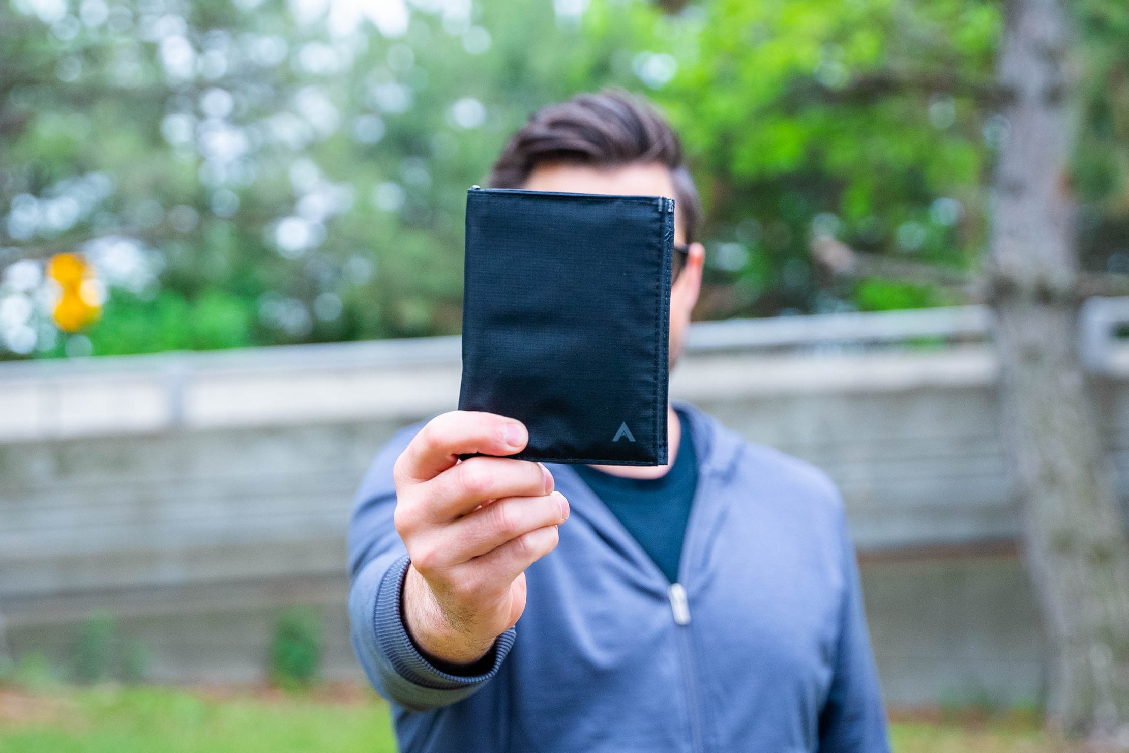 Allett nylon travel wallet held up in front of a guys face Gifts for Men