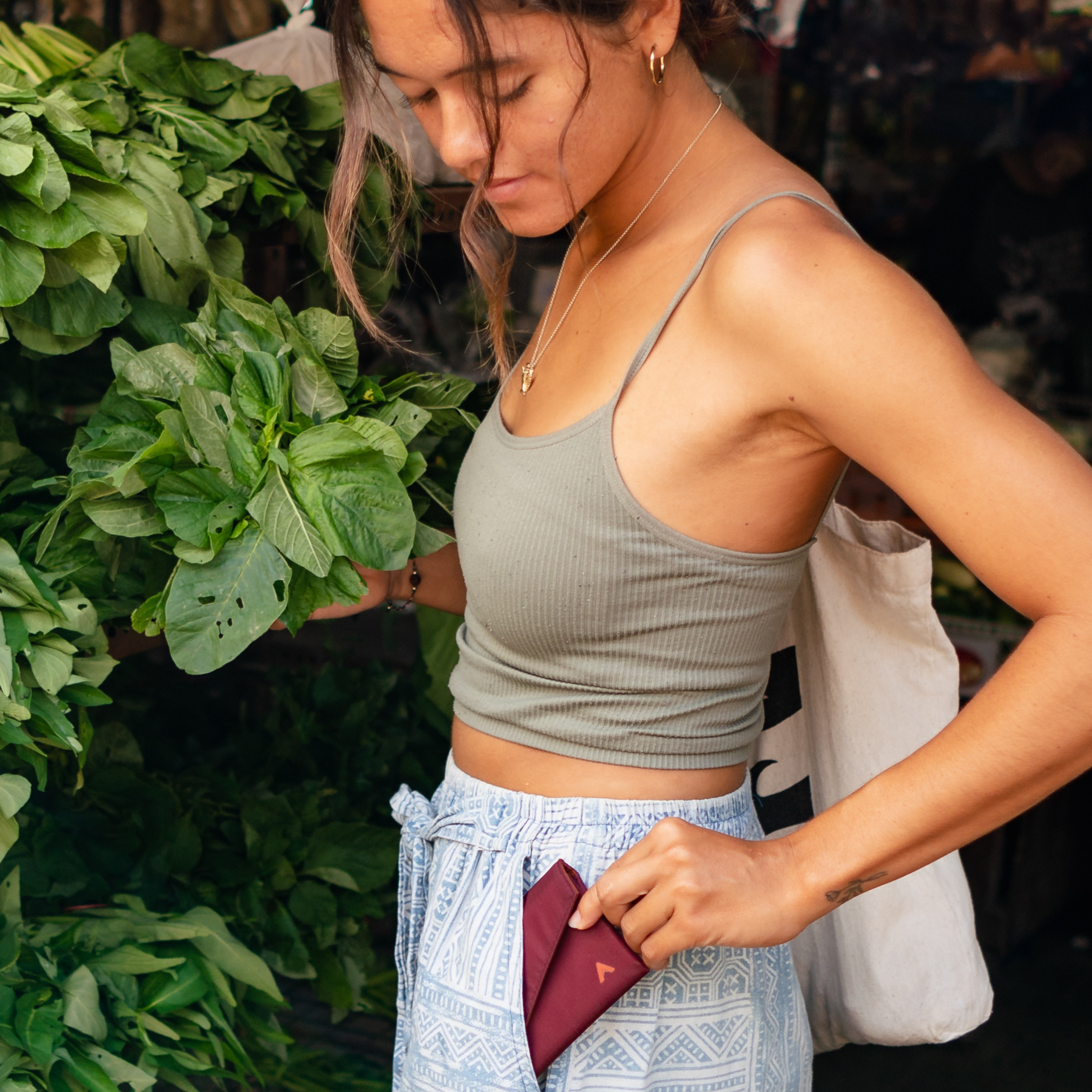 Woman shopping for greens at a market stall pulling out her slim allett wallet