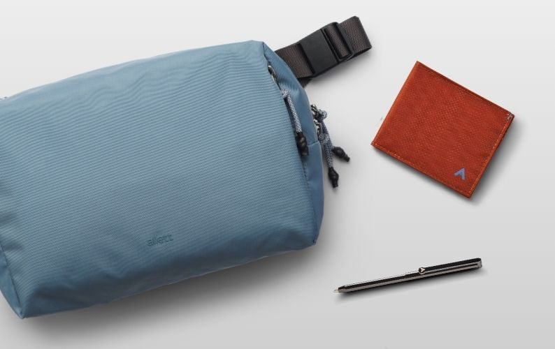 Blue pouch, red wallet, and black pen on a light gray background