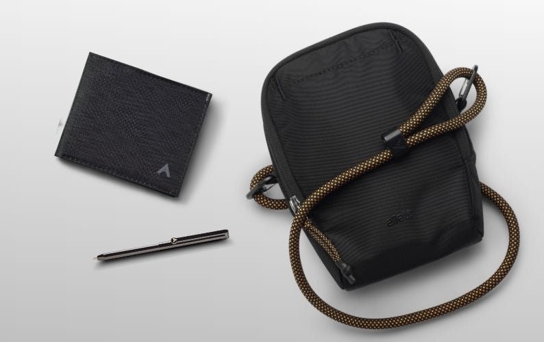 Black wallet, black pouch with rope handle, and pen on a light gray background