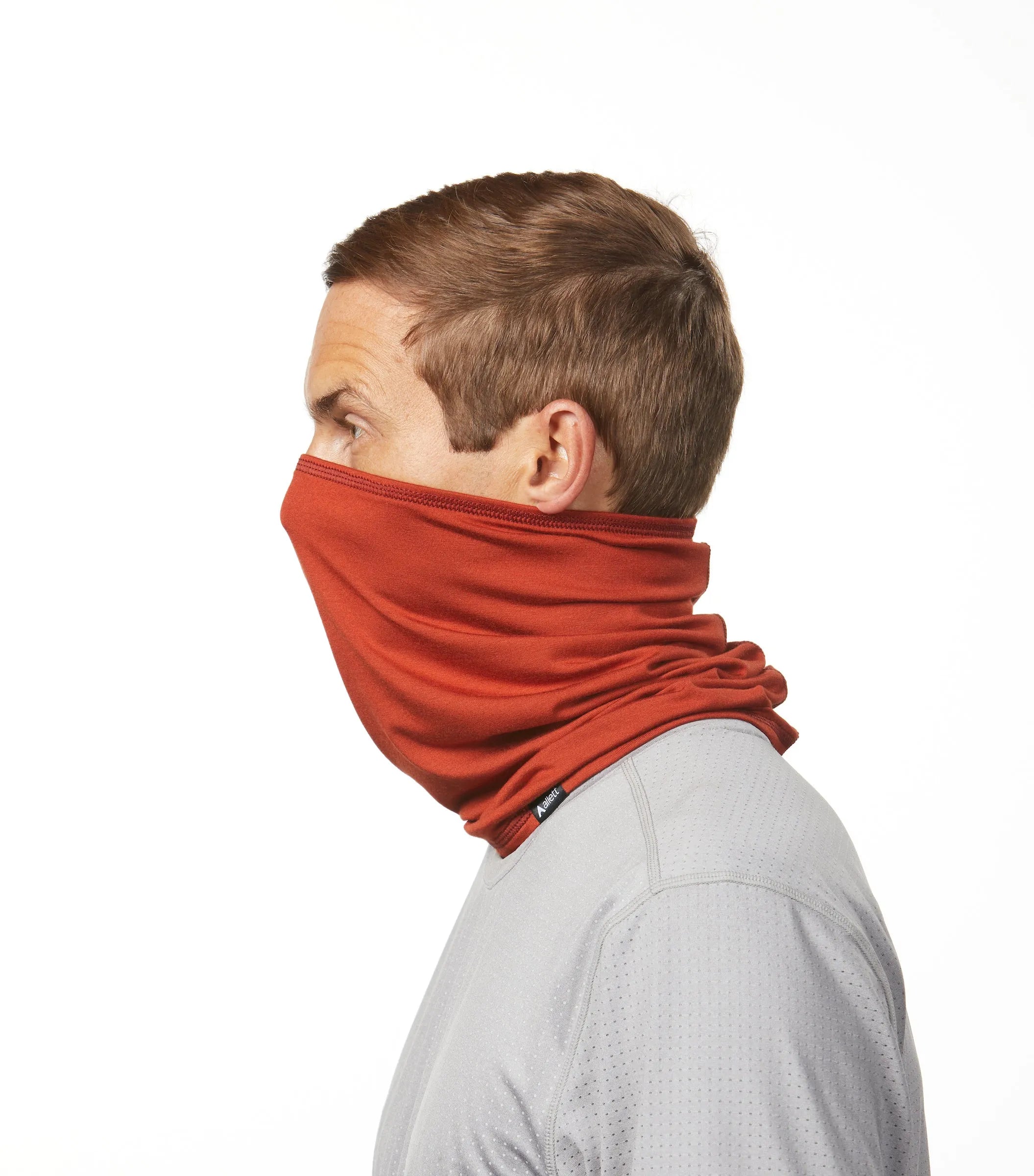 Man facing left that has a beautiful rust colored face covering that covers him from nose to neck. rust